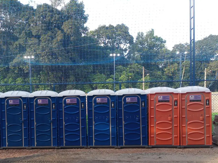 Sete banheiros químicos da FR Renovar, azuis e laranjas, instalados lado a lado
